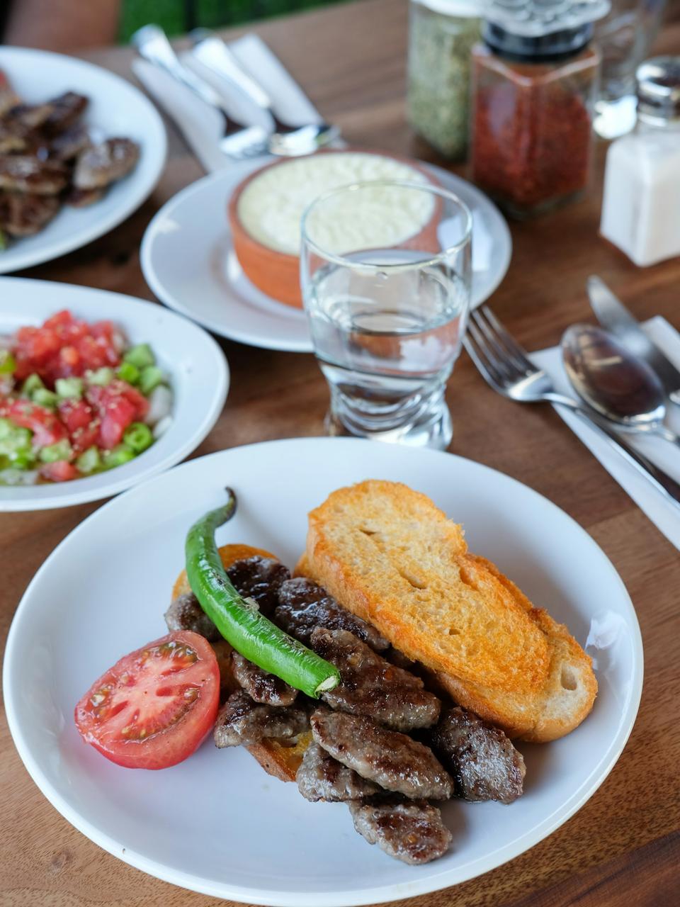Demo-Foto: Teller mit gegrilltem Fleisch, Brot, Tomate und grüner Peperoni